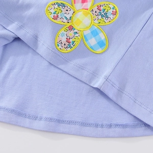 Detail of lavender cotton dress featuring colorful floral patchwork and yellow stitching