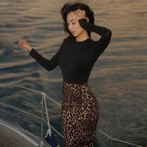 Detail view of a slim-fit leopard print skirt paired with a black long-sleeve top on a yacht