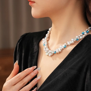 Dettaglio di una collana vintage di perle e grani blu indossata su un abito con scollo a V