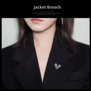 Detailed view of a silver heart brooch with rhinestones worn on a black blazer lapel