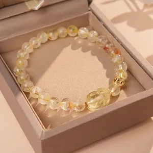 Golden rutilated quartz bead bracelet with carved PiXiu and hollow coin accent in a jewelry box