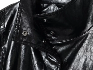 Detail of metal snap buttons and fine stitching on the black leather bomber jacket collar