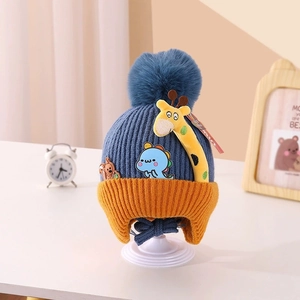 Detailed close-up of knitted ear-protection hat with giraffe doll and blue pompom