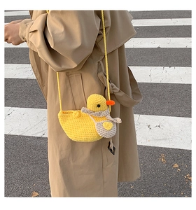 Close-up of handmade crochet yellow duck bag featuring a grey scarf and knitted texture