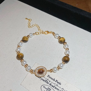 Gros plan d'un bracelet en oeil de tigre avec perles et billes dorées sur toile