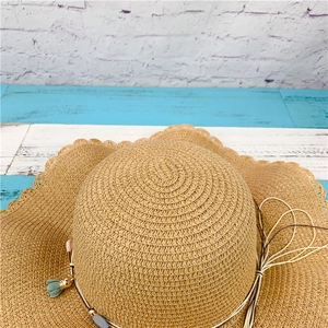 Detail of hand-woven straw sun hat showing raffia texture and tassel decoration