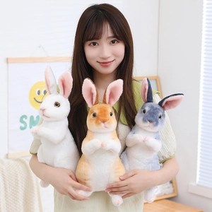 Three plush bunny dolls in white orange and grey held by a model for size display