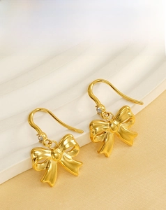 Macro detail of gold bow earrings with a single sparkling crystal on elegant hooks