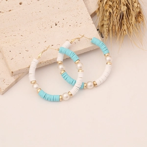 Detail of bohemian hoop earrings with blue heishi beads and pearls on stone base