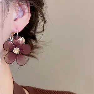 Mesh flower earrings with sparkling rhinestone center on elegant model ear side view