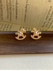 Macro shot of gold-plated rocking horse stud earrings with sparkling cubic zirconia
