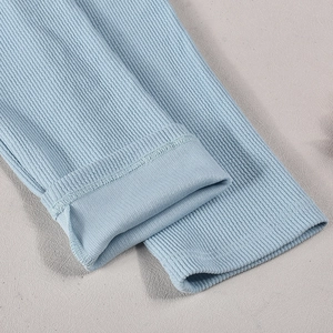 Macro detail of light blue ribbed knit fabric showing fine stitching and soft texture