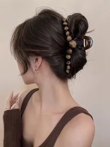 Close-up of a large amber-colored claw clip with beads worn on a woman's hair