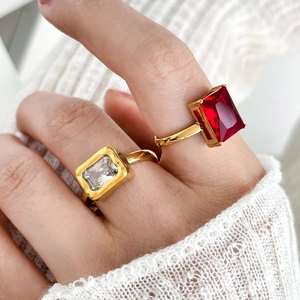 Close-up of gold titanium rings with red and white rectangular zircon on a hand