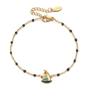 Detailed close-up of golden stainless steel bracelet with black beads and sailboat charm