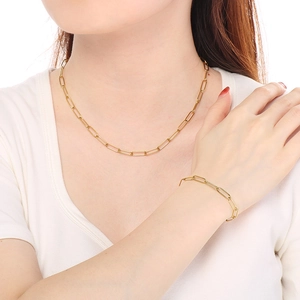 Close-up of golden stainless steel paperclip chain necklace and bracelet on model