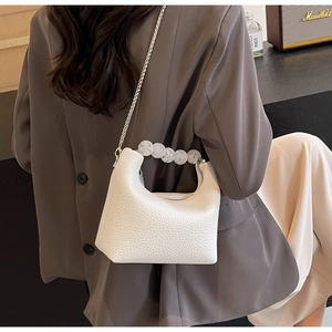 Detail of white lychee leather texture with pearl handle and silver chain strap