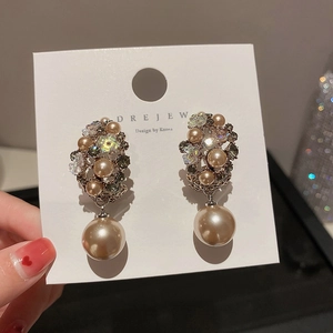 Detailed close-up of floral crystal earrings with a champagne faux pearl drop pendant