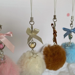 Detailed close-up of colorful plush fur ball phone charms with bows and star pendants