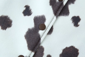 Gros plan d'une veste à motif vache avec boutons bruns et détails de coutures zigzag