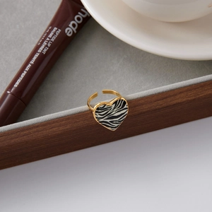 Detail of gold heart ring with zebra print inlay displayed on grey felt tray