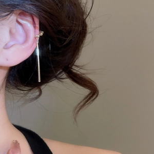 Détail d'un long clip d'oreille doré avec zircons élégants et accents de perles fines