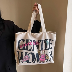 Detail of beige canvas tote bag featuring Gentle Woman text and cheerleader bear print