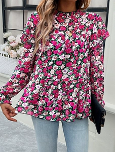 Detail of floral long sleeve blouse featuring ruffled stand collar and layered hem design