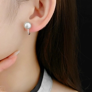 Close-up of elegant silver U-shaped clip-on earring featuring a white pearl on ear