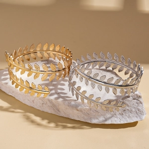 Adjustable gold and silver leaf branch cuff bracelets on a natural stone base