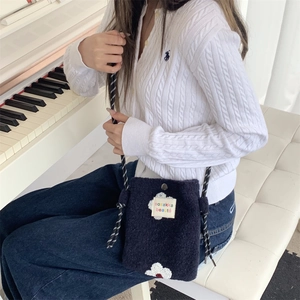 Macro detail of navy plush crossbody bag featuring white 3D flowers and woven shoulder strap