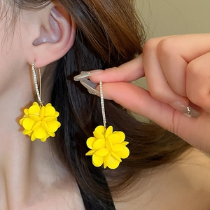 Detail of yellow flower drop earring with crystal paved stud on woman's ear