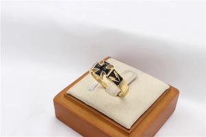 Detailed close-up of gold steel ring with black enamel cross and lightning patterns
