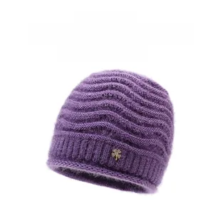 Dettaglio del berretto in maglia viola con motivo a onde e ciondolo a quadrifoglio