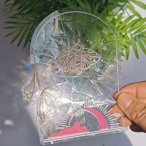 Macro detail of holographic moth suncatcher showing rainbow light refraction on static film