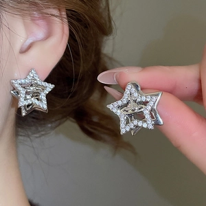 Macro view of sterling silver star stud earrings with saturn ring and zircon stones