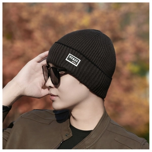 Close-up of ribbed knit beanie texture in dark brown with a stylish side fabric label
