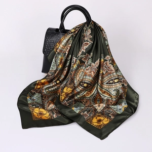 Detail of dark green paisley silk scarf draped over a black crocodile pattern handbag