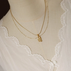 Close-up of double-layer gold snake chain necklace with irregular metal pendant on model