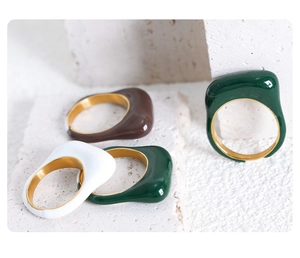 Detail of wavy enamel rings in green, white, and brown with gold plating on stone