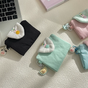 Close-up of pastel nylon wallets with plush trim and cute animal charms on a desk