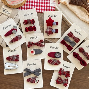 Bow and heart shaped fabric hair clips in red and grey plaid on a vintage wood desk