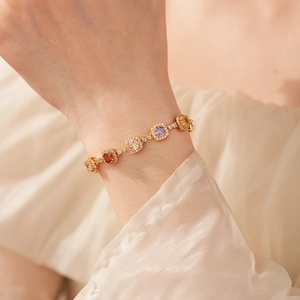 Close-up of a vintage gold chain bracelet featuring colorful square-cut gemstones and pavé accents