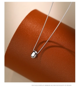 Macro detail of mirror-polished silver bean pendant on 925 sterling silver chain