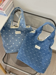 Tragetaschen aus Denim mit weißen Stern- und Schleifenmustern auf hellblauem Stoff
