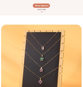 Detail view of gold necklaces with floral and gemstone pendants on a black jewelry stand