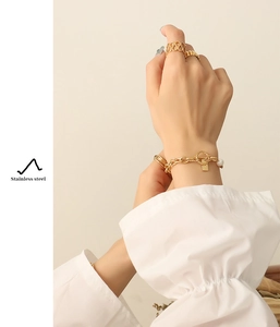 Detail of gold stainless steel toggle clasp bracelet and rings worn on hand