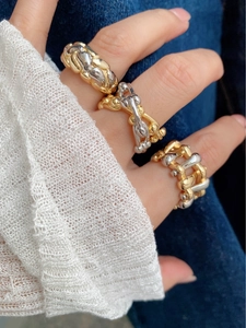 Detailed view of two-tone chunky woven chain rings on model wearing denim and white