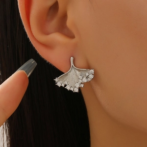 Close-up of a silver ginkgo leaf earring featuring shimmering zircon stones on a model
