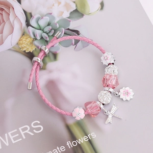 Detailed macro view of pink braided leather bracelet with dragonfly and floral charms